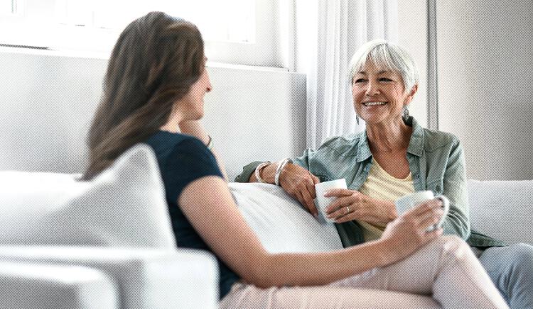 A caregiver and her mother sit on a couch drinking coffee A caregiver and her mother sit on a couch drinking coffee